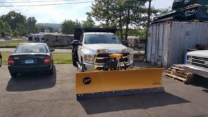 Yellow Fisher straight plow attached to a white truck.