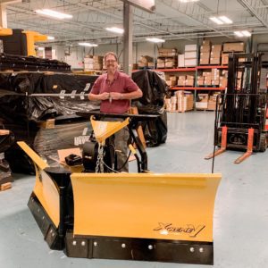 A man standing behind an "Xtreme V" v-plow by Fisher.