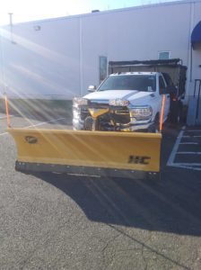 White work truck that has a Fisher straight plow attached.