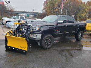 A Fisher "Xtreme V" v-plow attached to the front of a black truck.